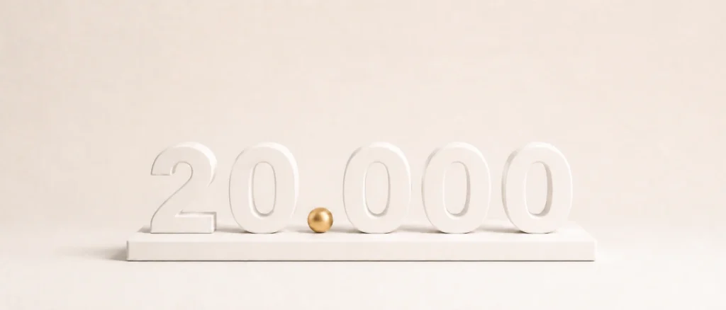 20.000 Euro anlegen: Mattweiße Zahl 20.000 mit goldenem Punkt auf einem kompakten cremefarbenen Podest.